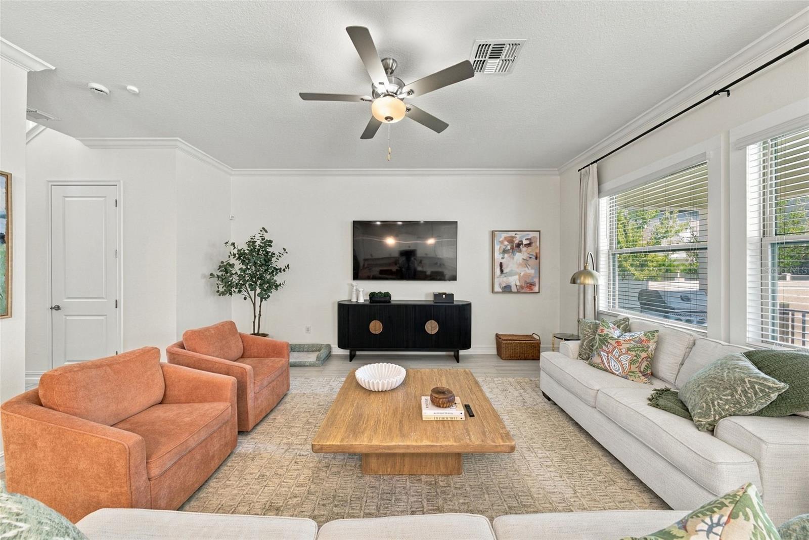Living room with rust-colored armchairs, a light sectional, and a wooden coffee table.