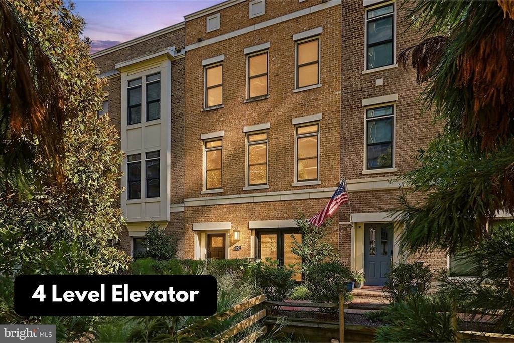 Brick townhouse with a U.S. flag, landscaped entry, and four-level elevator feature label.