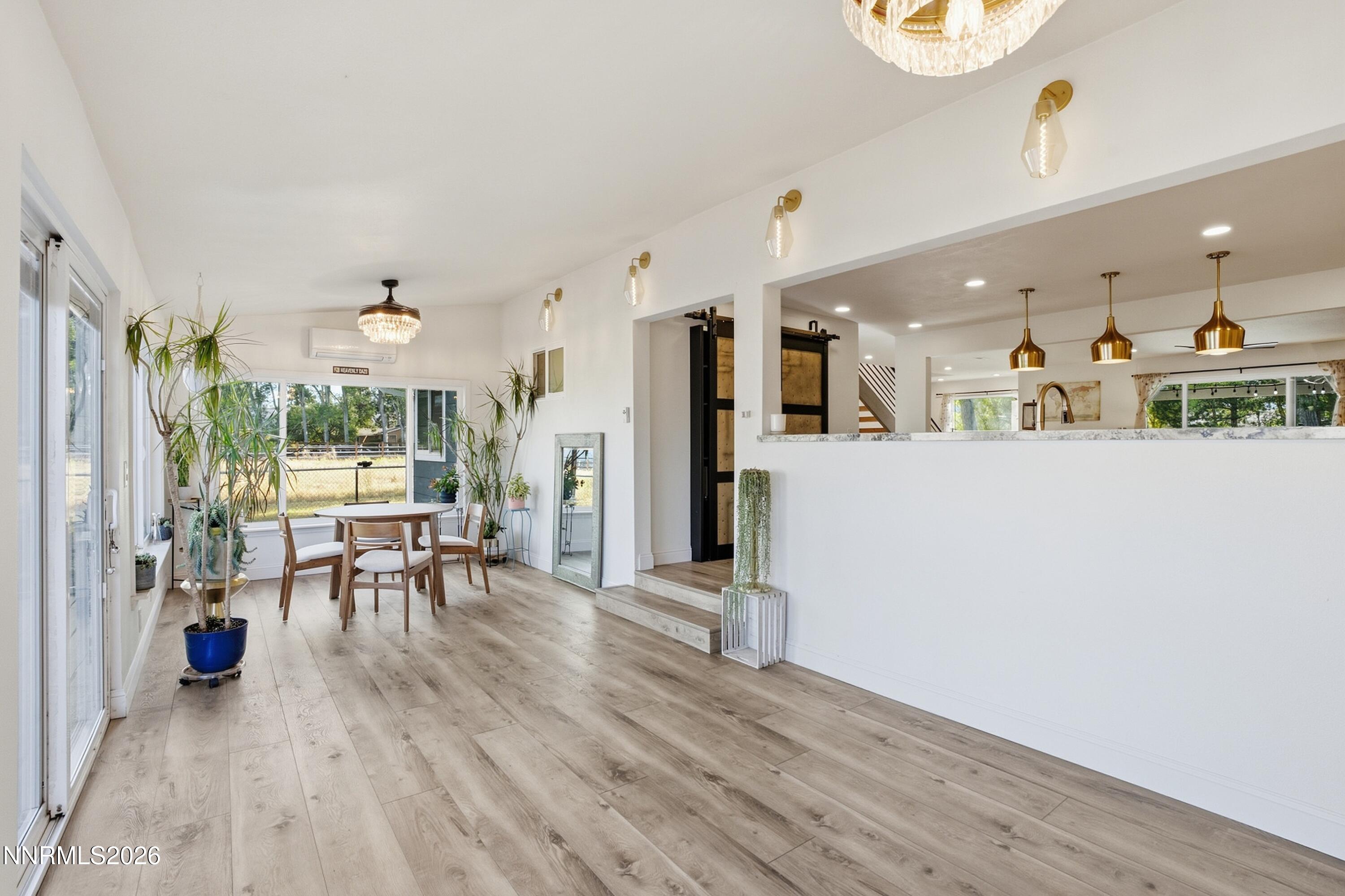 Open dining area with wood table, sliding glass doors, and gold pendant lights over the kitchen counter.