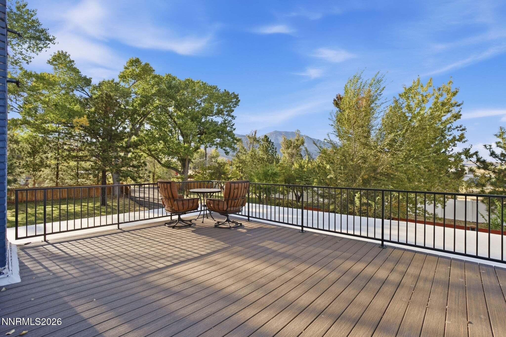 Outdoor deck with two swivel chairs, wooded surroundings, and a mountain view.