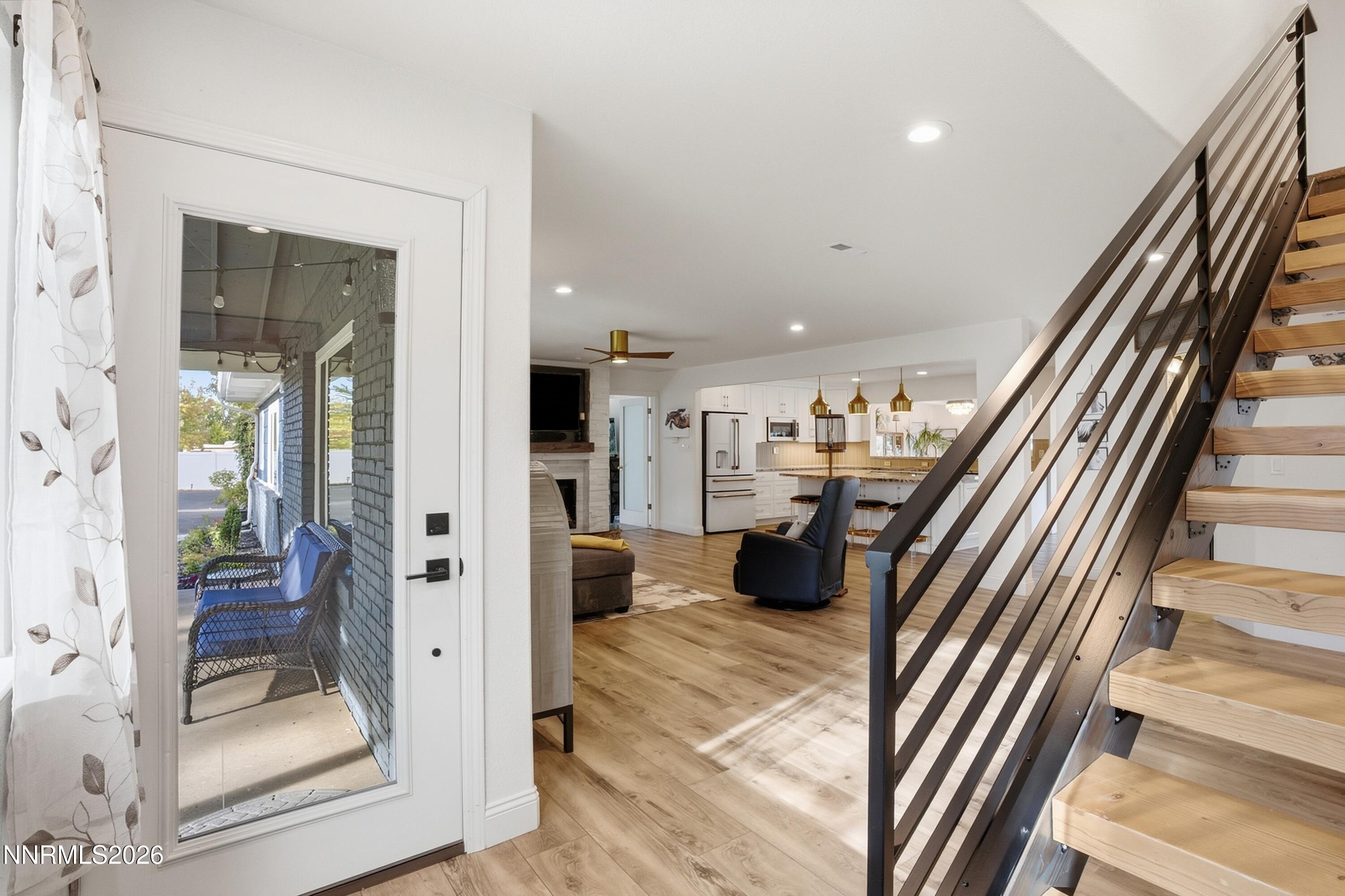 Open-plan living room and kitchen with a floating wood staircase and glass door to the patio.