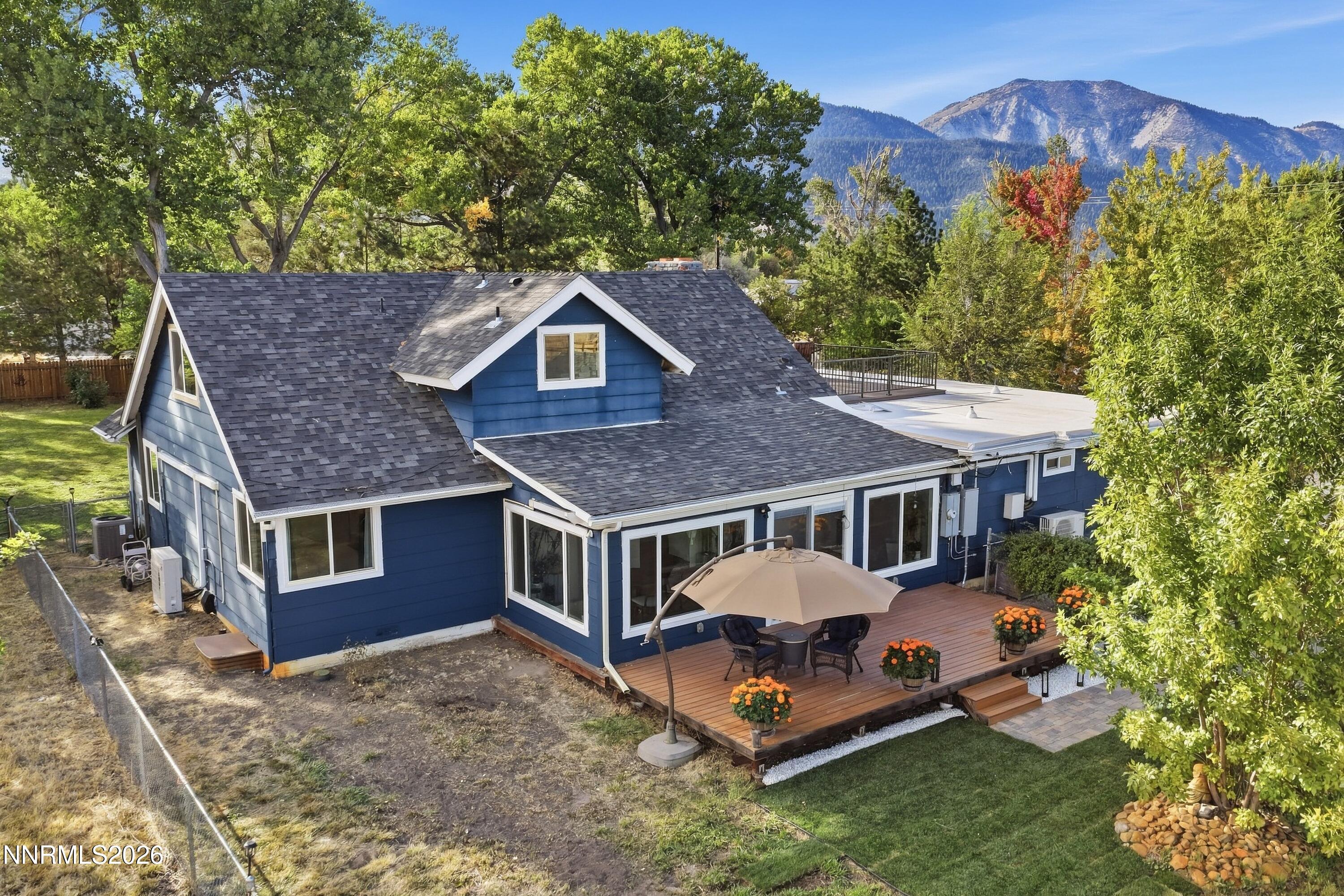 Blue house with a furnished rear deck, rooftop terrace, and mountain views.