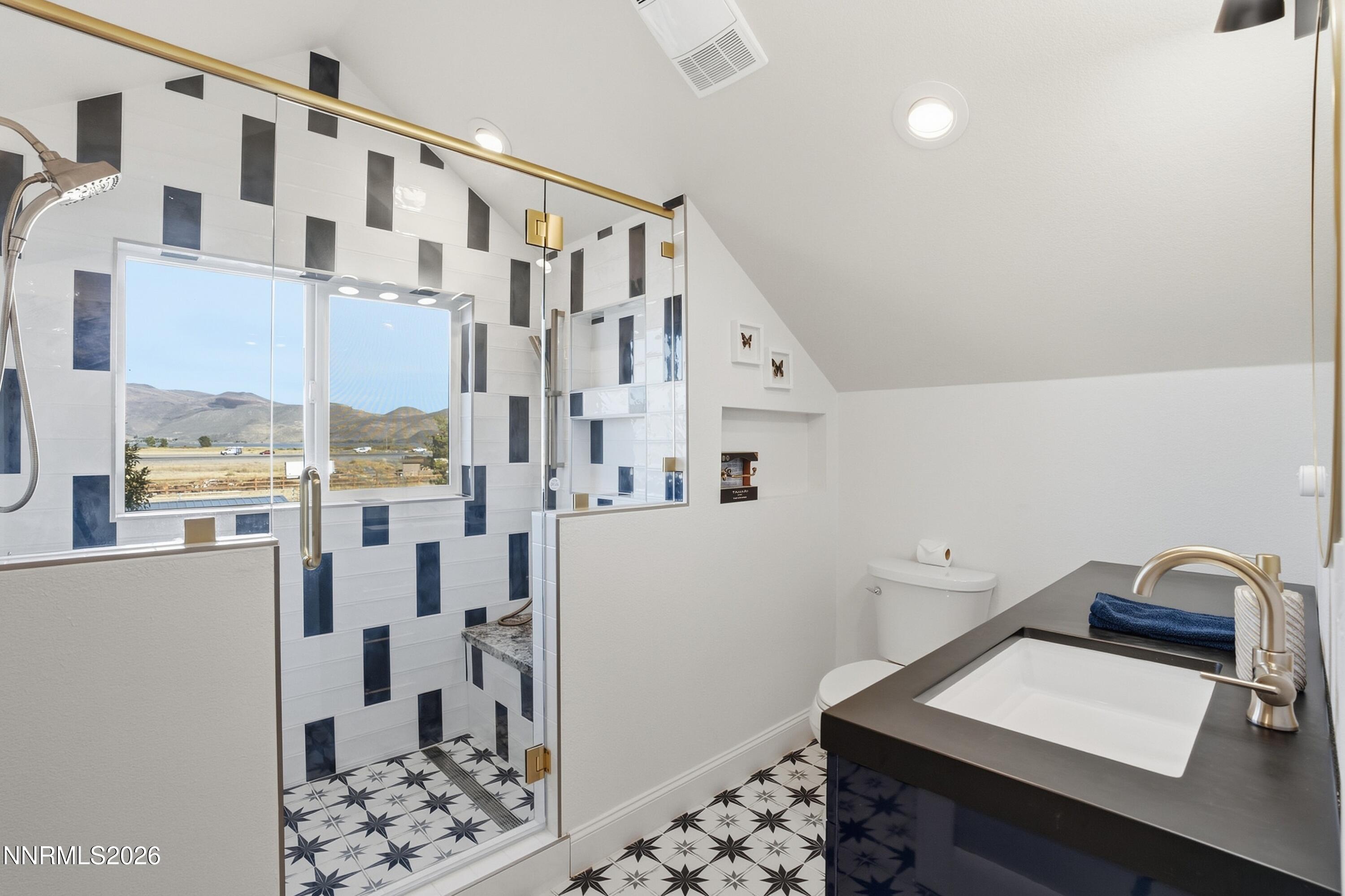 Bathroom with a geometric-tile glass shower, star-patterned floor, and valley views through the window.