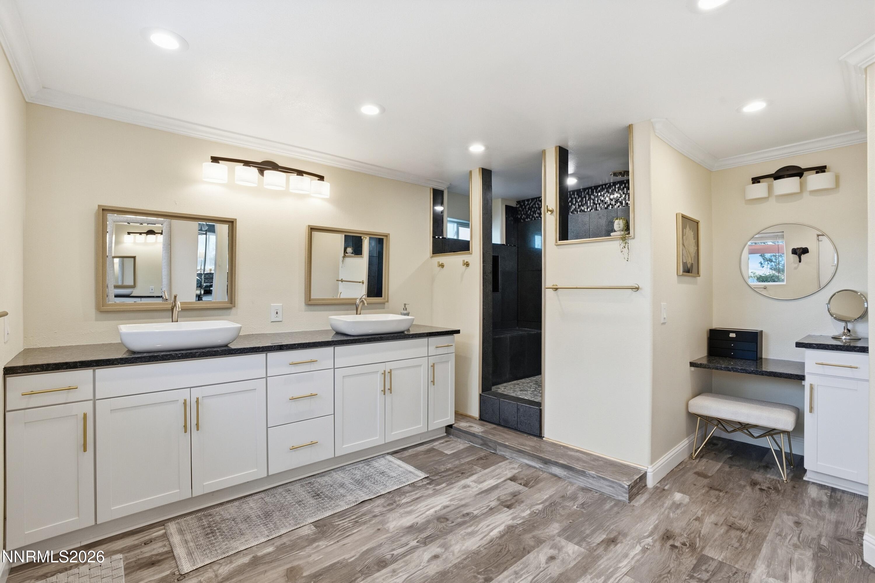 Remodeled bathroom with a double vessel-sink vanity, dark tiled shower, and built-in makeup station.