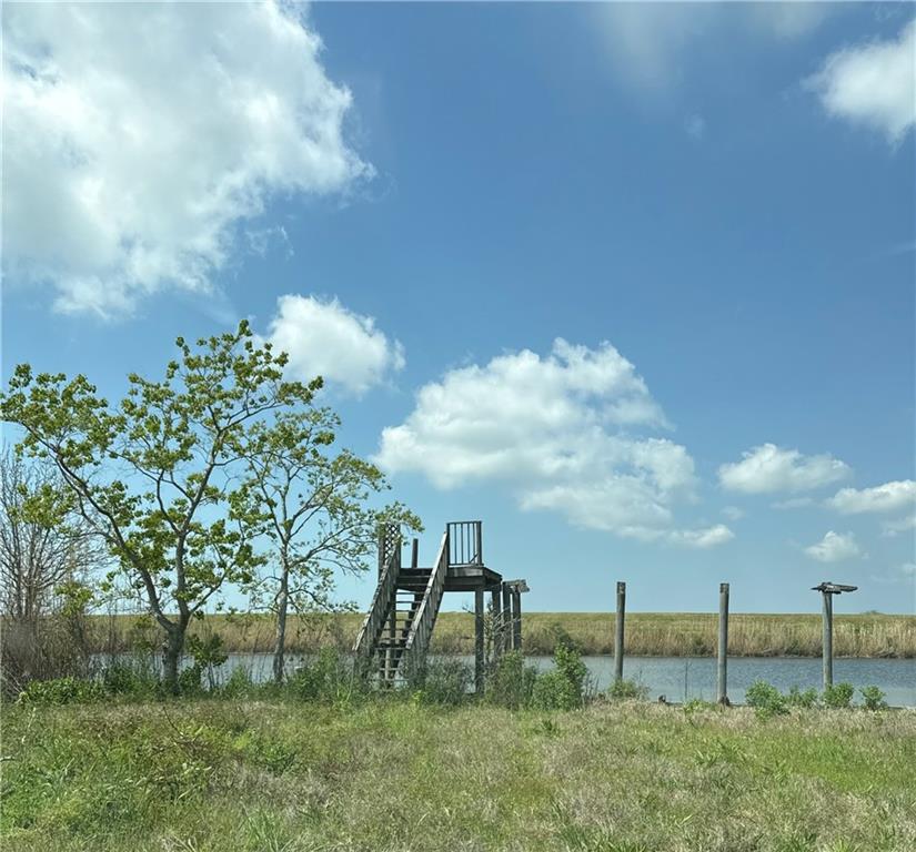 Waterfront property with a wooden stair platform beside a canal and marshland beyond.