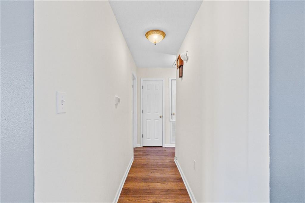Hallway with hardwood floors leading to a white door.