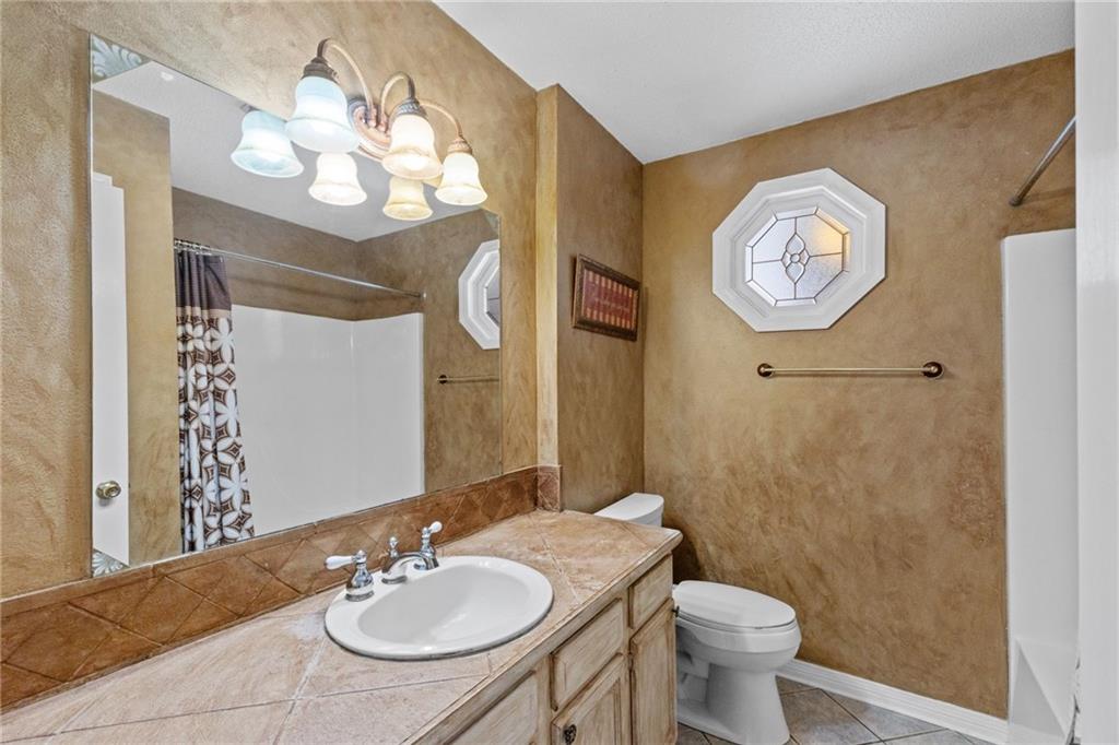 Bathroom with a long tiled vanity, large mirror, and octagonal window.