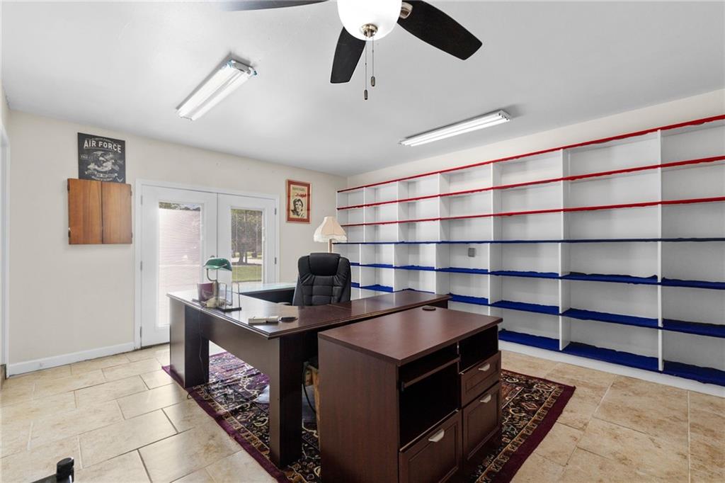 Home office with a large dark wood desk and wall-length shelving with red and blue trim.