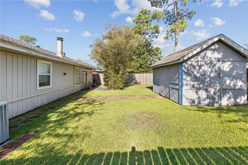 Backyard with a grassy lawn, detached gray shed, and wooden privacy fence.