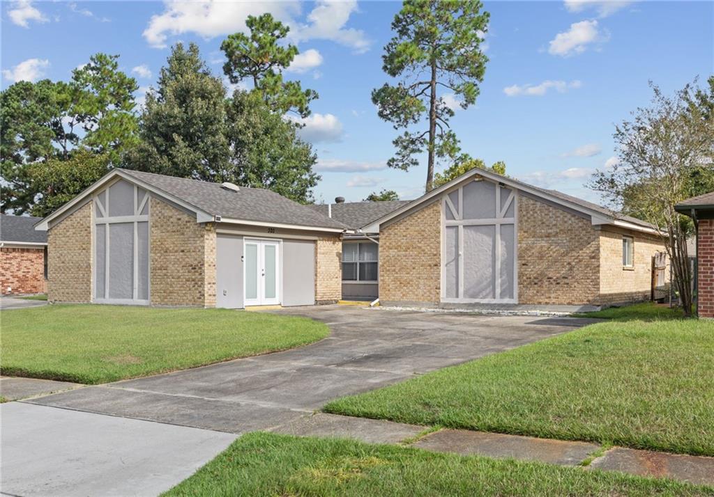 Tan brick home with twin white-trimmed front gables, driveway, and lawn.