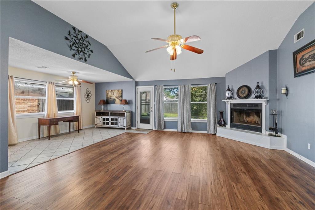 Living room with vaulted ceiling, blue-gray walls, wood-look floors, and a fireplace.