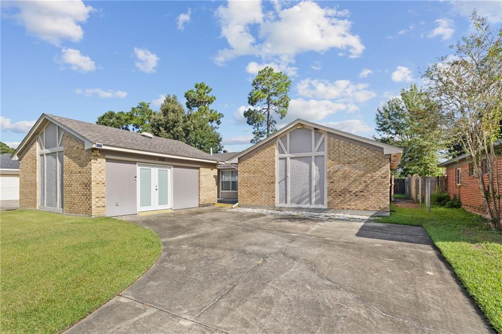 Brick property with white gable trim and a broad concrete driveway.