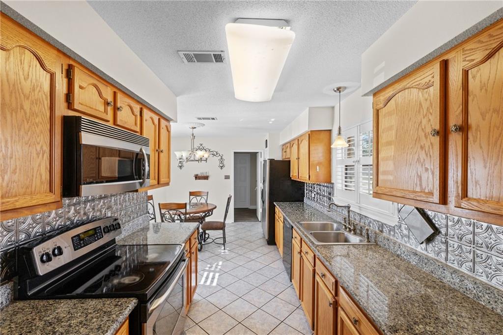 Kitchen with wood cabinets, granite counters, stainless steel appliances, and a small dining nook.