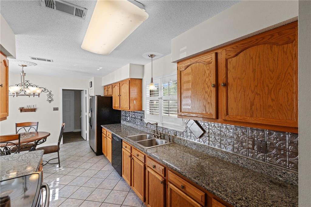 Kitchen with wood cabinets, granite counters, decorative backsplash, and a double-basin sink.
