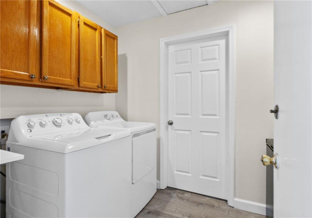 Laundry room with a white washer and dryer beneath wooden cabinets.