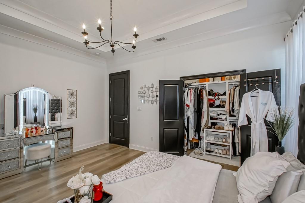 Bedroom with a mirrored vanity, open closet, and chandelier.
