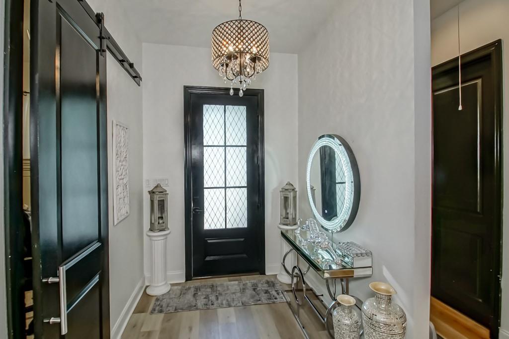 Entryway with a black glass-paneled front door, chandelier, and mirrored console table.