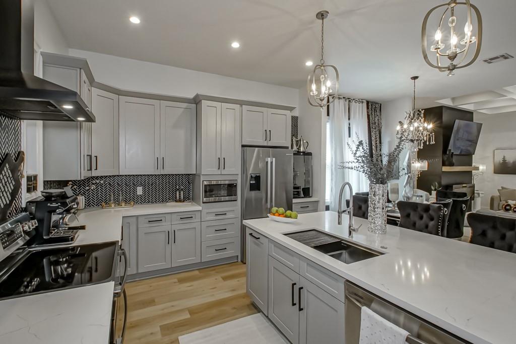 Modern kitchen with gray cabinets, herringbone backsplash, and a large white island.