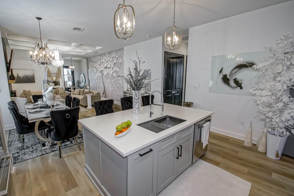 Open-plan kitchen with a white island and sink beside a furnished dining area.