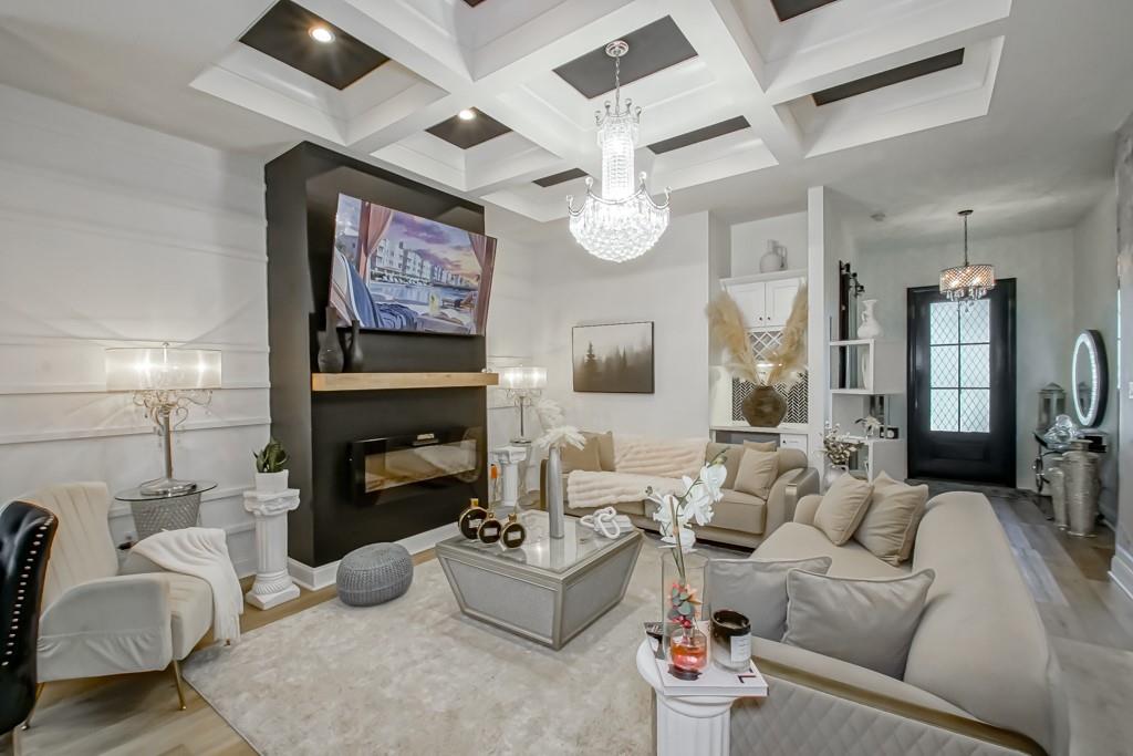 Living room with beige seating, a dark fireplace wall, and a crystal chandelier.