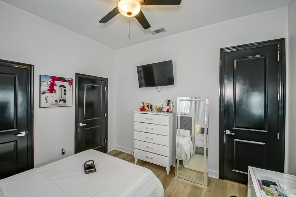 Bedroom with black paneled doors, a white dresser, and a wall-mounted television.