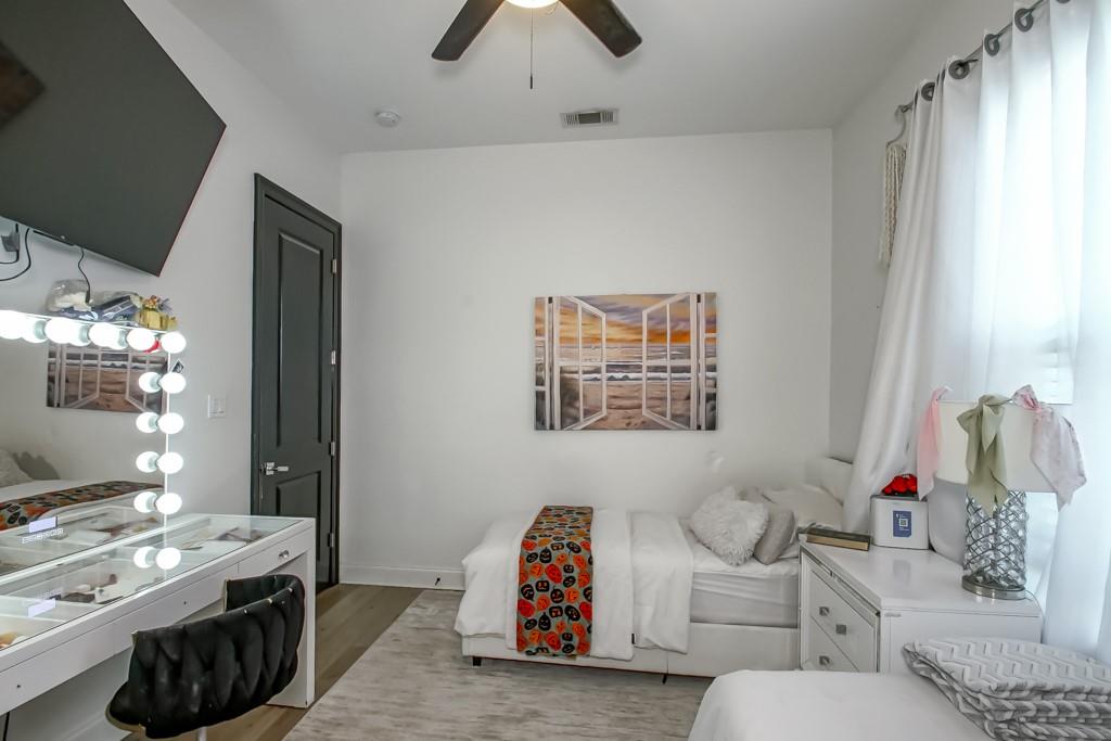 Bedroom with a lighted vanity, white bed, and colorful patterned runner.