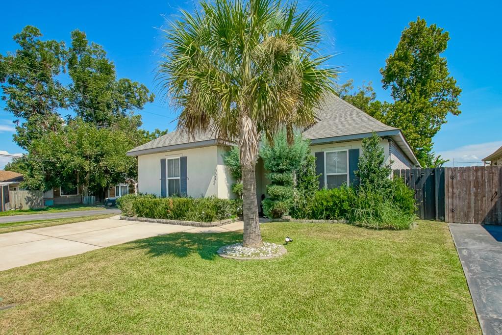 Single-story house with a large palm tree in the front lawn and a wide concrete driveway.