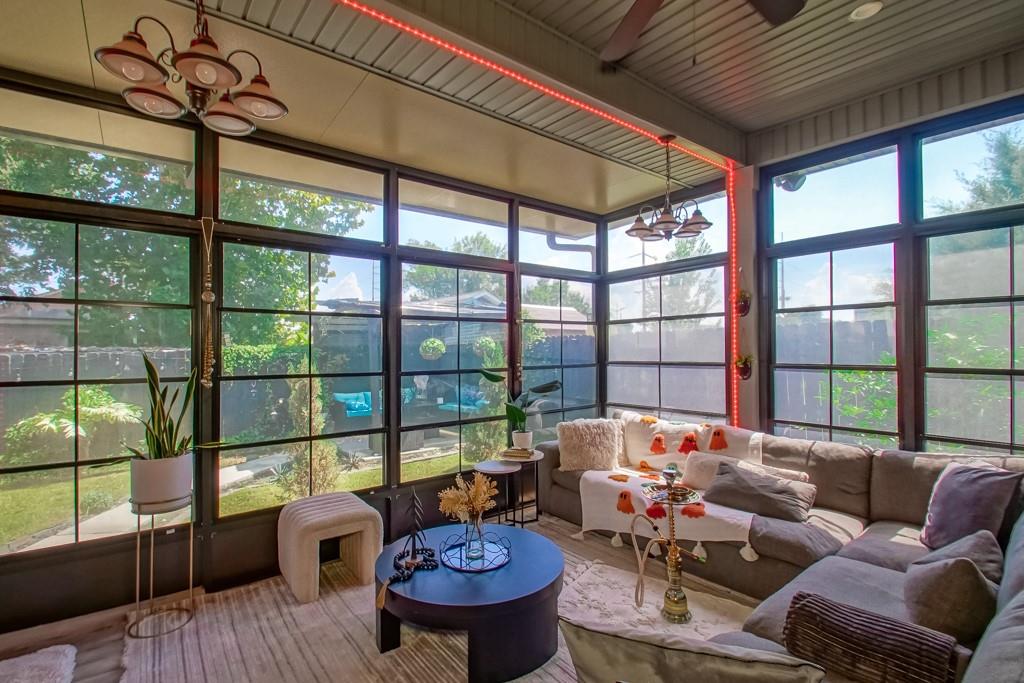 Sunroom with a gray sectional, round coffee table, and floor-to-ceiling windows overlooking the backyard.