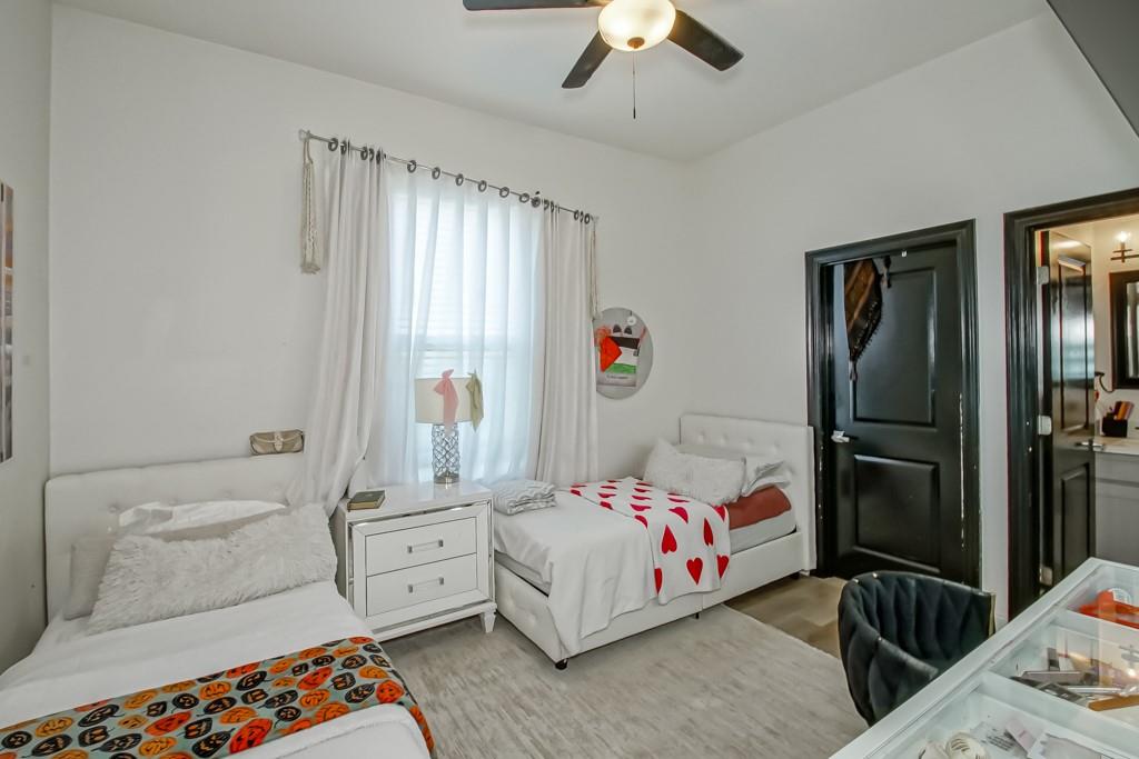 Bedroom with two white twin beds, sheer curtains, and a red heart-patterned blanket.