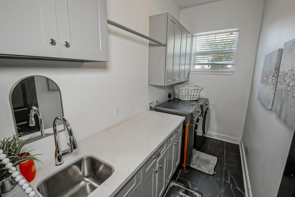 Laundry room with a long white countertop, utility sink, and washer and dryer.
