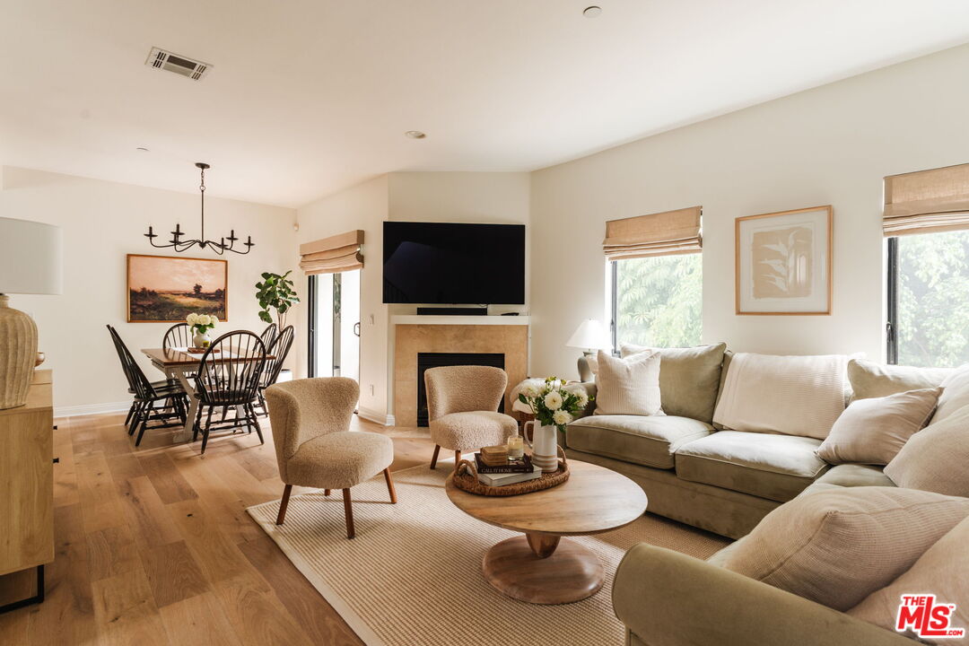 Open-plan living and dining room with a beige sectional, fireplace, and large television.