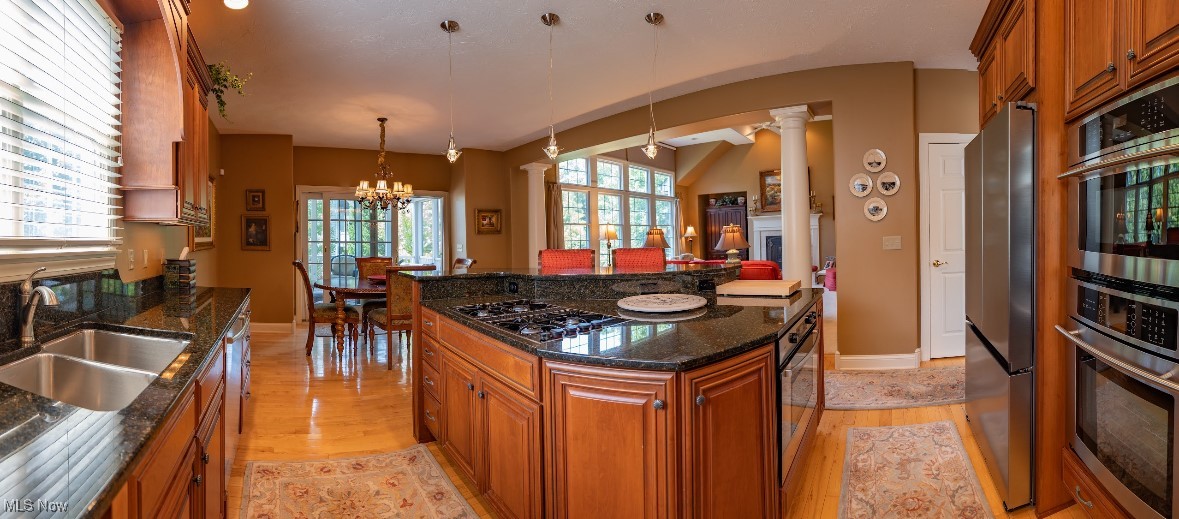 Kitchen with a granite island, gas cooktop, wood cabinetry, and adjoining dining area.