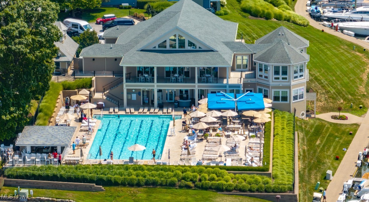 Clubhouse and outdoor swimming pool with patio seating and blue umbrellas.