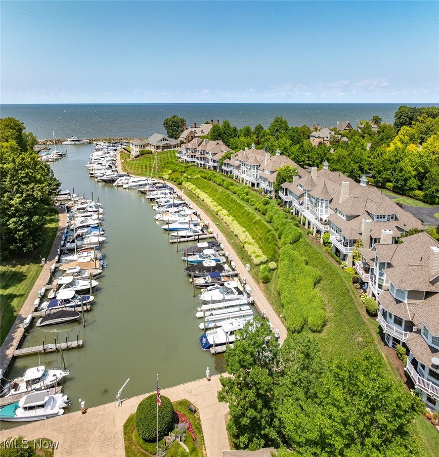 Waterfront homes line a marina filled with boats, with open water beyond.