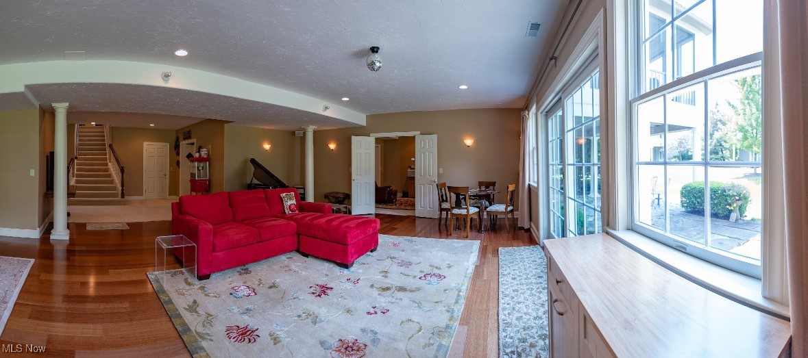 Living room with a red sectional, floral rug, hardwood floors, and tall windows.