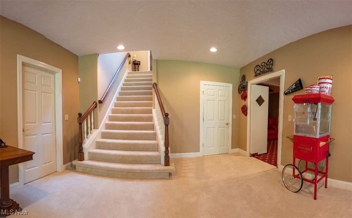 Foyer with a carpeted staircase and a red popcorn machine on wheels.