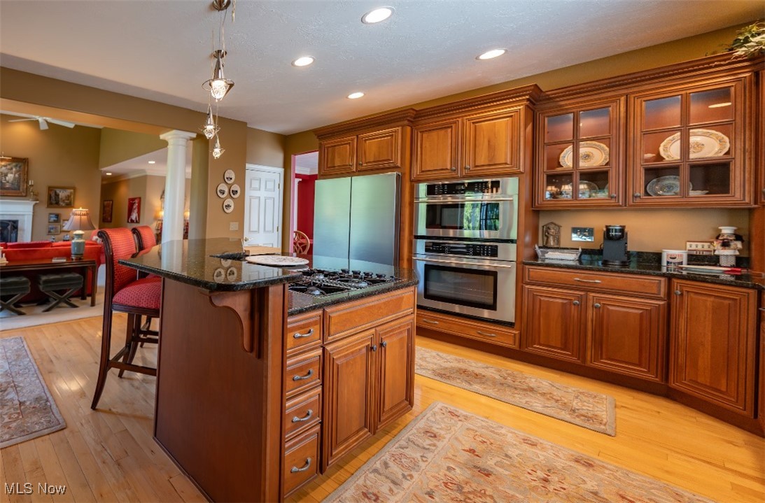 Kitchen with rich wood cabinetry, a granite island, stainless steel appliances, and hardwood floors.