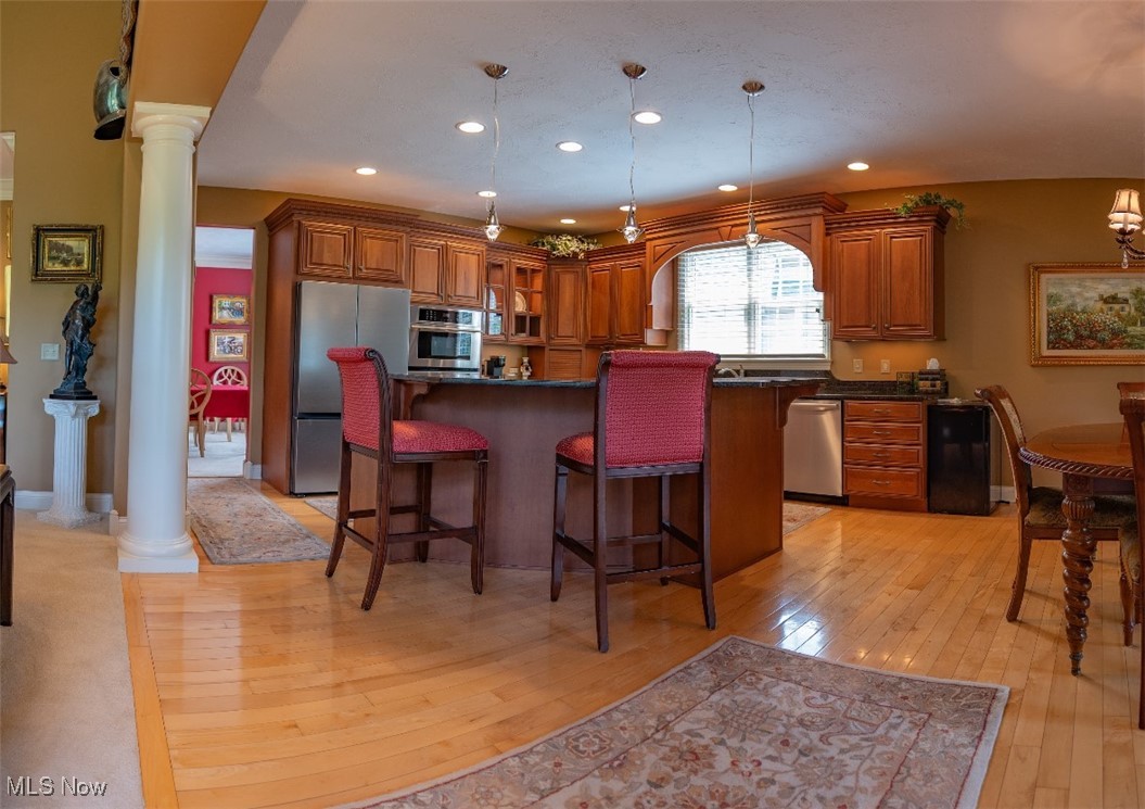 Kitchen with cherry cabinetry, stainless appliances, and a large island with red bar stools.