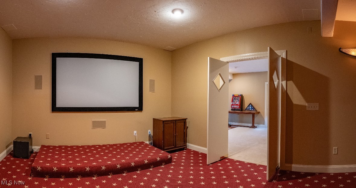 Home theater with a large projection screen, red star-patterned carpet, and open double doors.