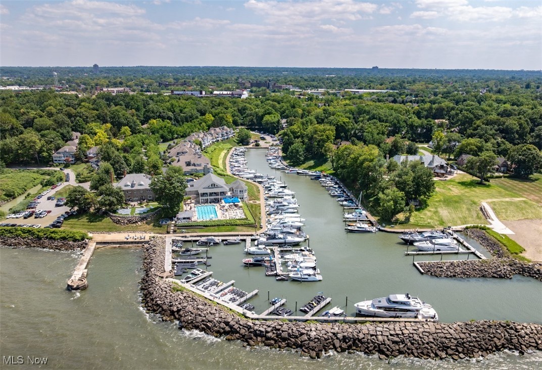Aerial view of a marina with rows of boats, a waterfront clubhouse, and a swimming pool.