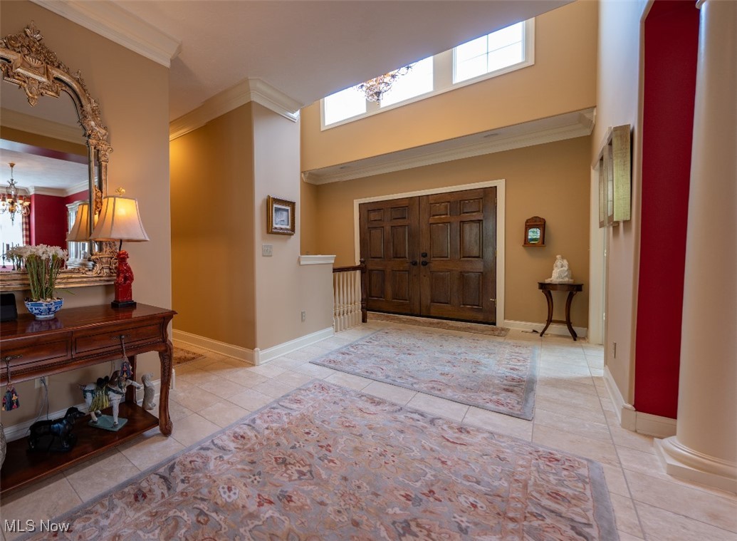 Entry foyer with dark double doors, clerestory windows, tiled floors, and patterned rugs.