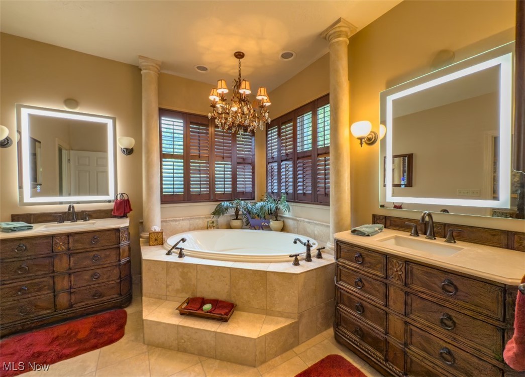 Primary bathroom with a raised corner soaking tub, dark wood vanities, and plantation shutters.