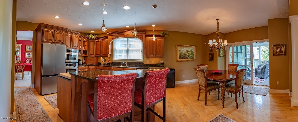 Open kitchen and dining area with wood cabinets, a granite island, red barstools, and sliding glass doors.