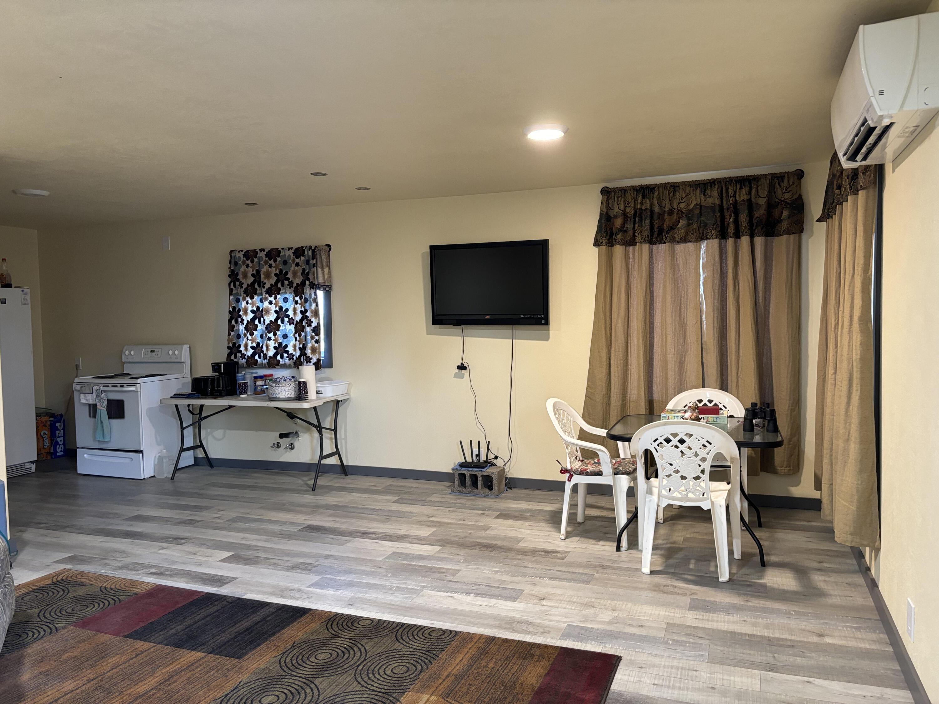 Kitchen and dining area with a wall-mounted TV, white stove, and plastic dining set.