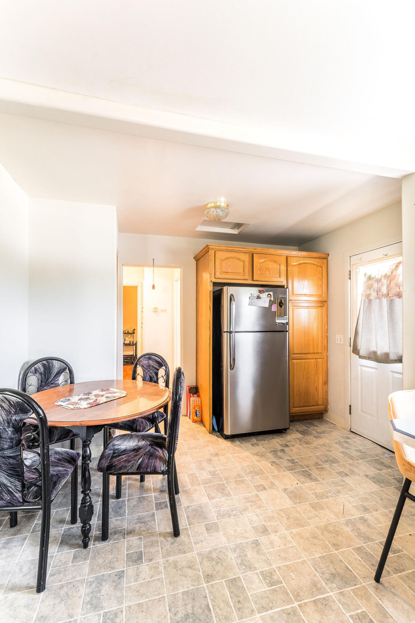 Kitchen and dining area with wooden cabinets, stainless steel refrigerator, and round table.