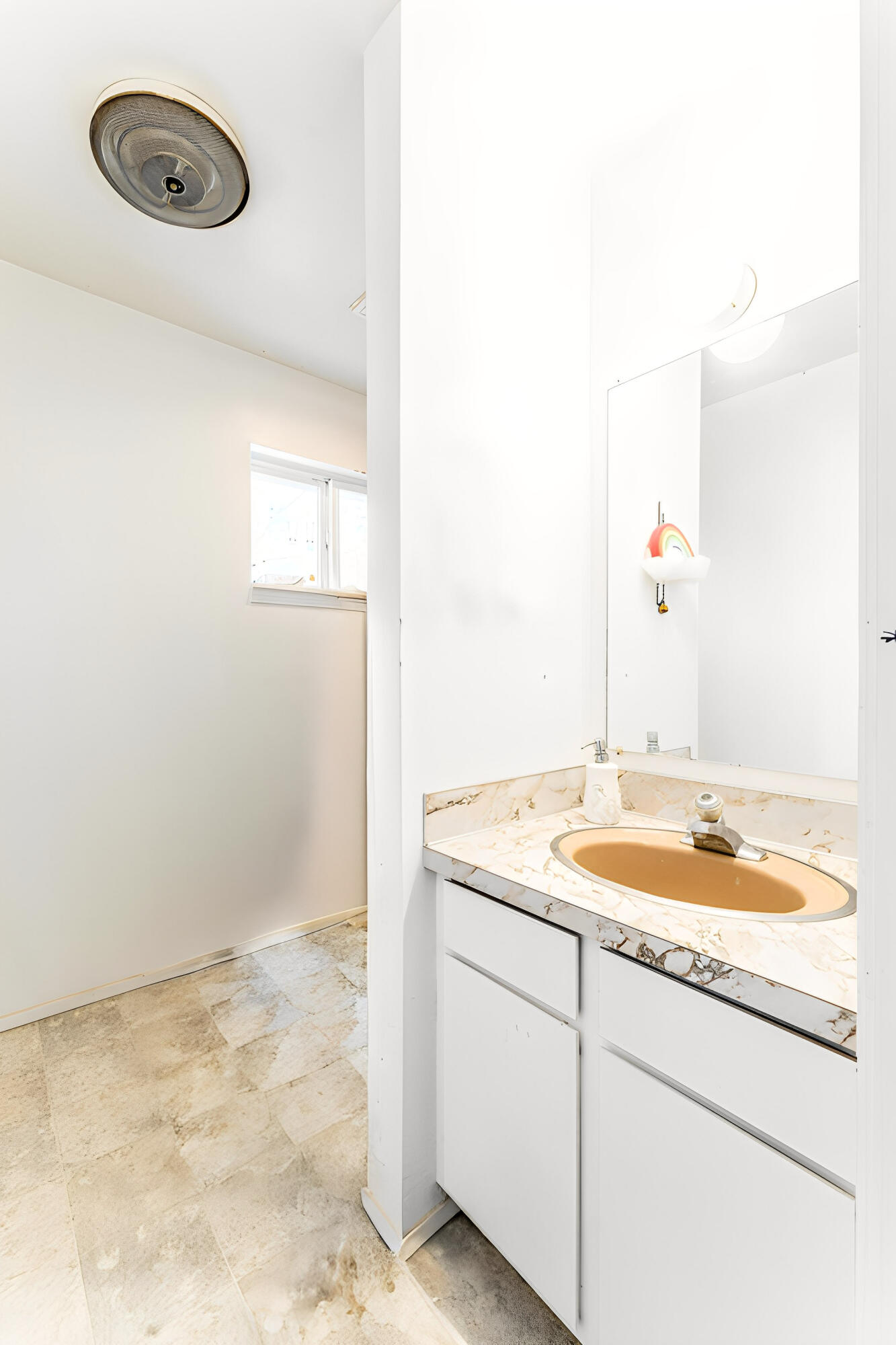 Bathroom vanity with a tan oval sink, marble-patterned countertop, and large mirror.