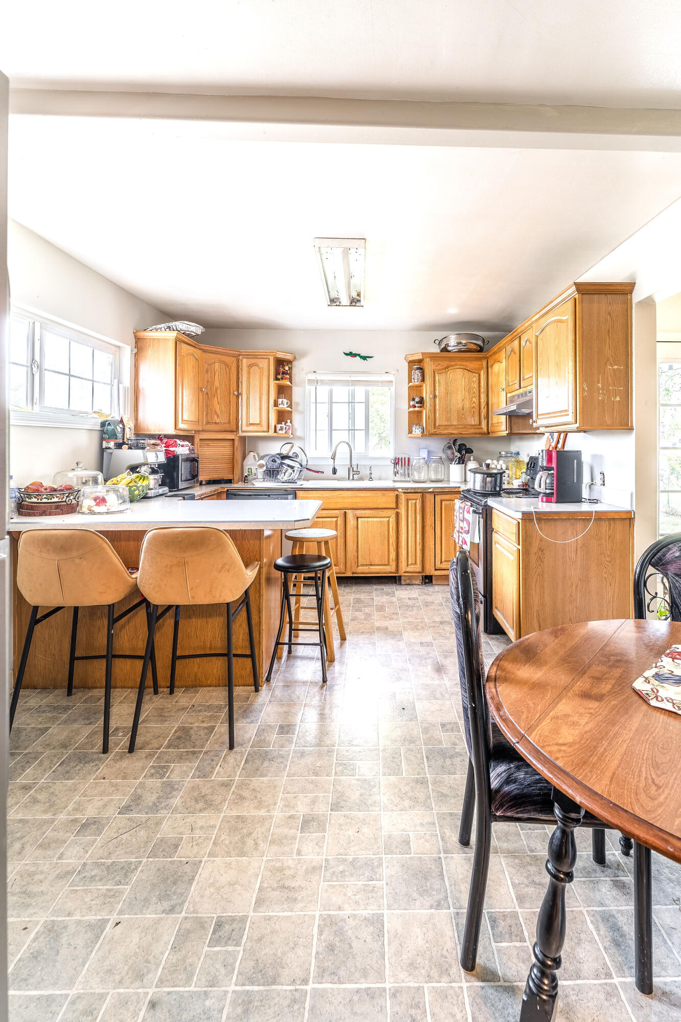 Kitchen with honey-toned cabinets, an island with upholstered stools, and an adjoining wooden dining table.