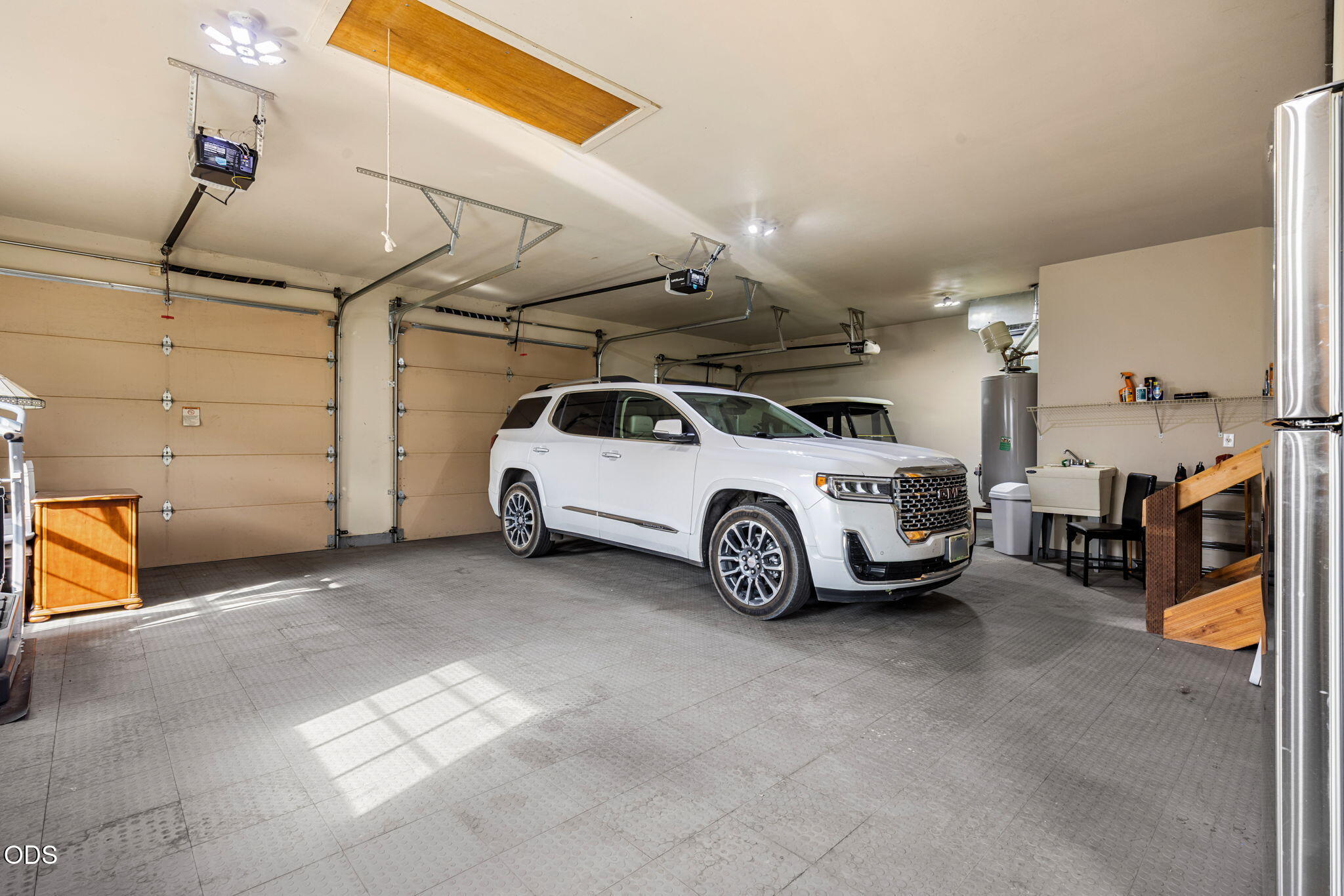 Spacious garage with a white SUV, tiled floor, and two garage doors.