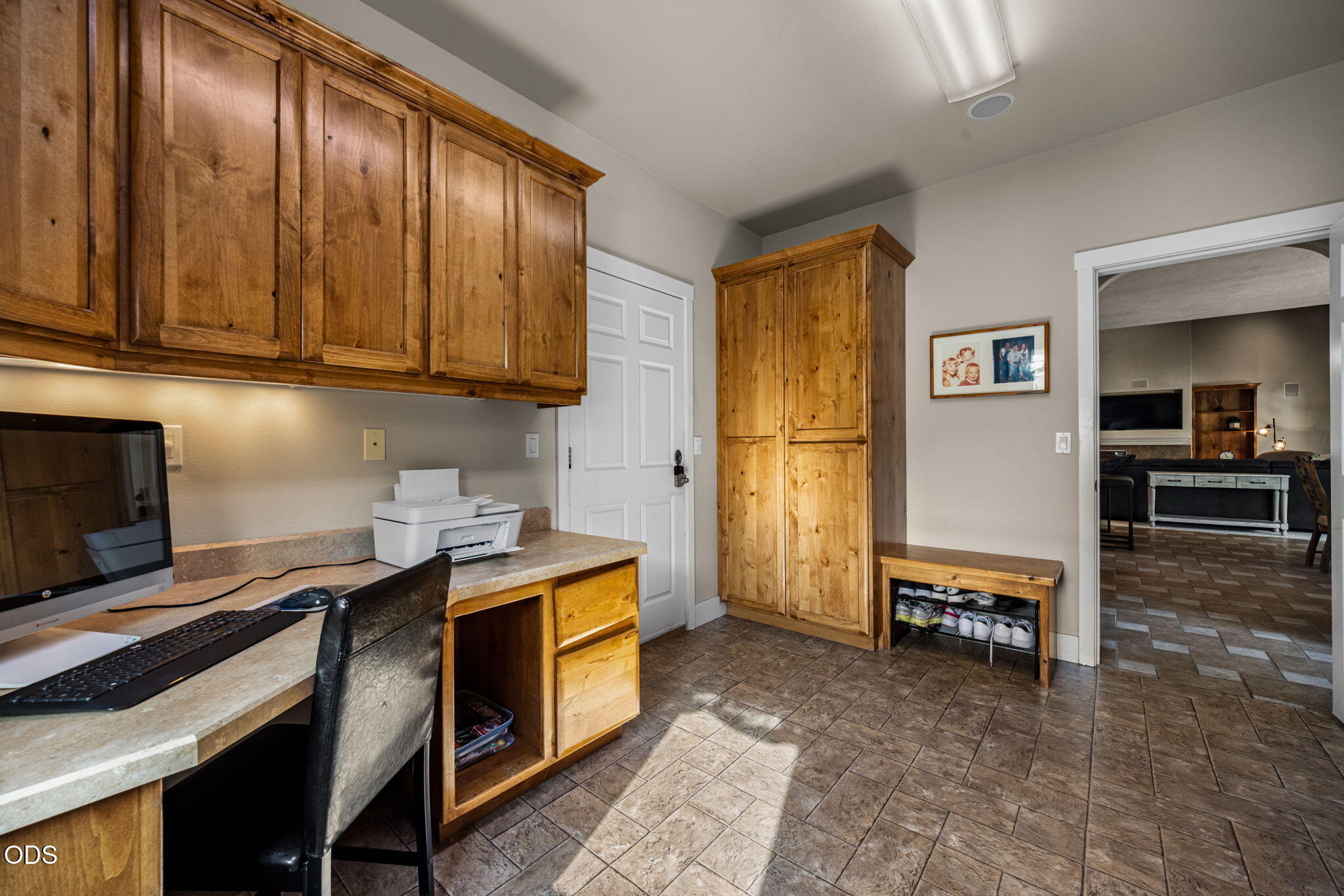 Built-in office and entry area with warm wood cabinetry, tiled floors, and a shoe bench.