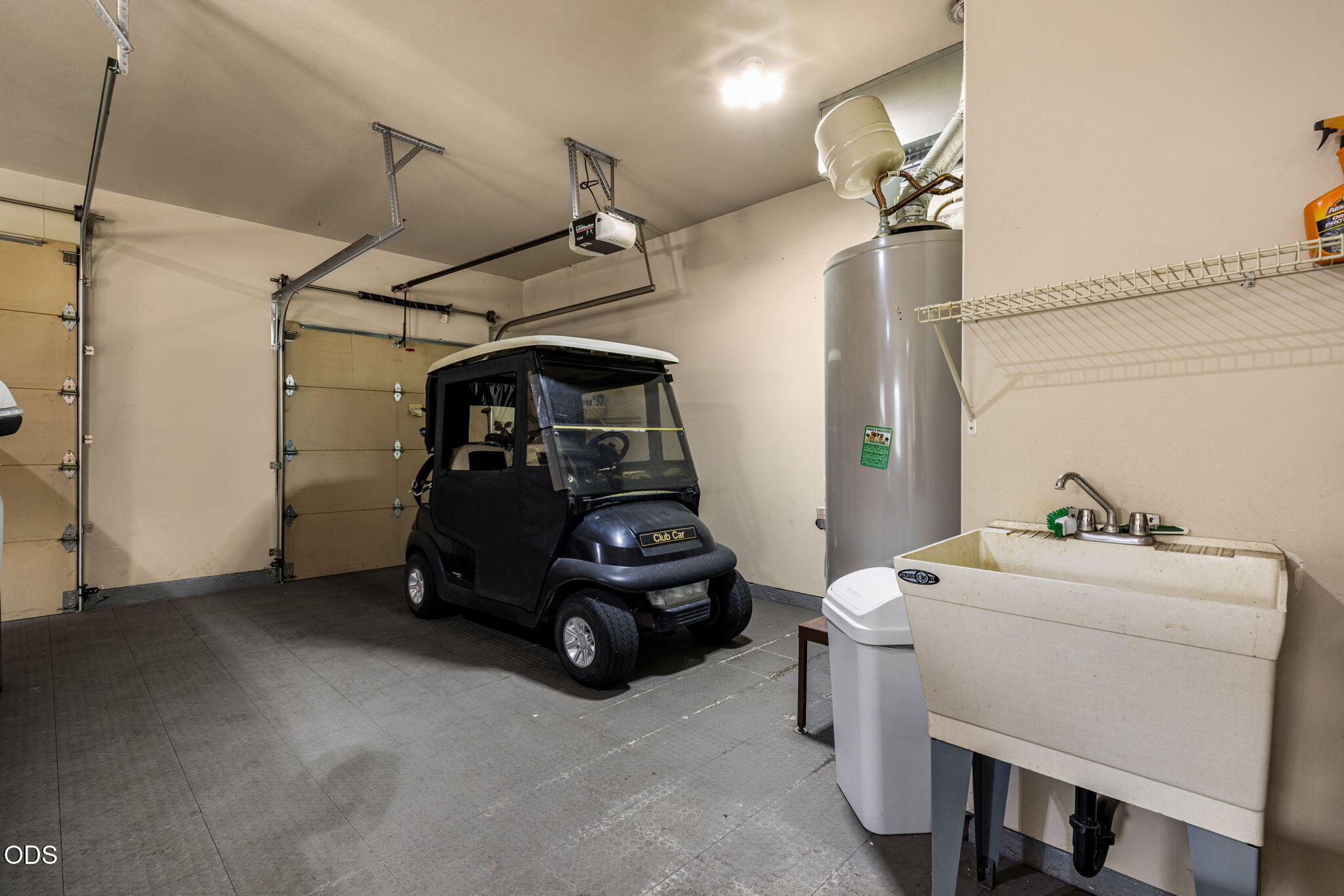 Garage with a black Club Car golf cart, utility sink, and water heater.